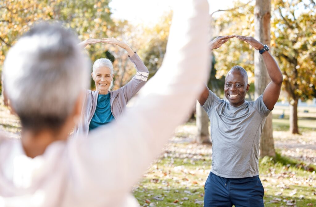 Seniors in the park are guided in a stretching and yoga routine.