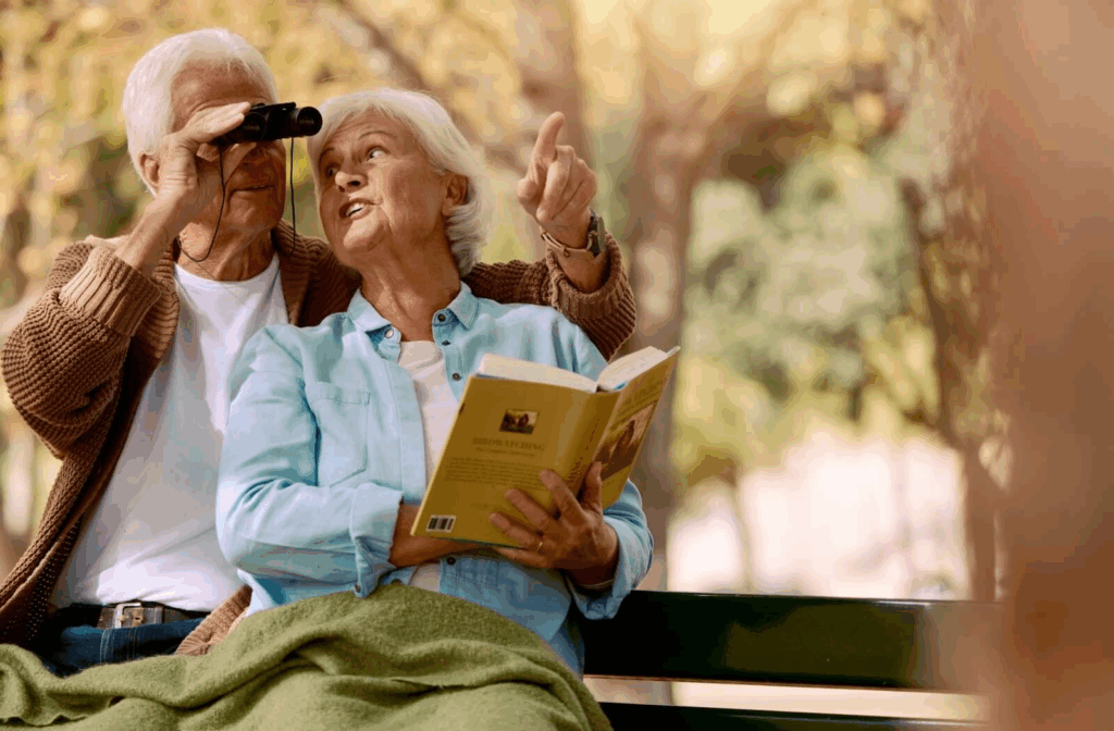 Two people are bird watching, one with the binoculars, the other with the field guide.